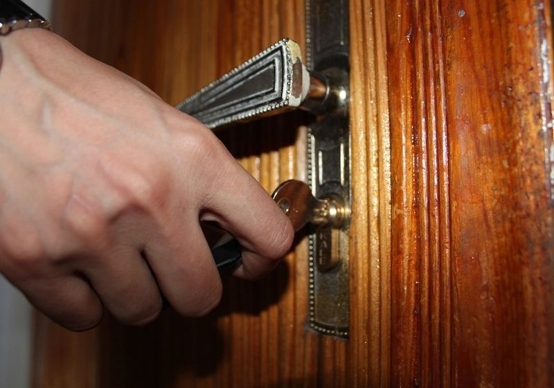 Hand turning a key in a wooden door lock